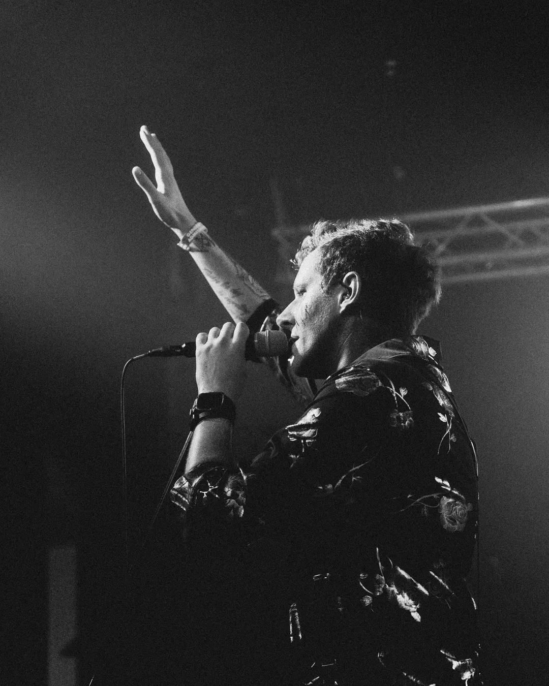 Black-and-white photo of Kyle singing on stage in Tucson, one arm raised
